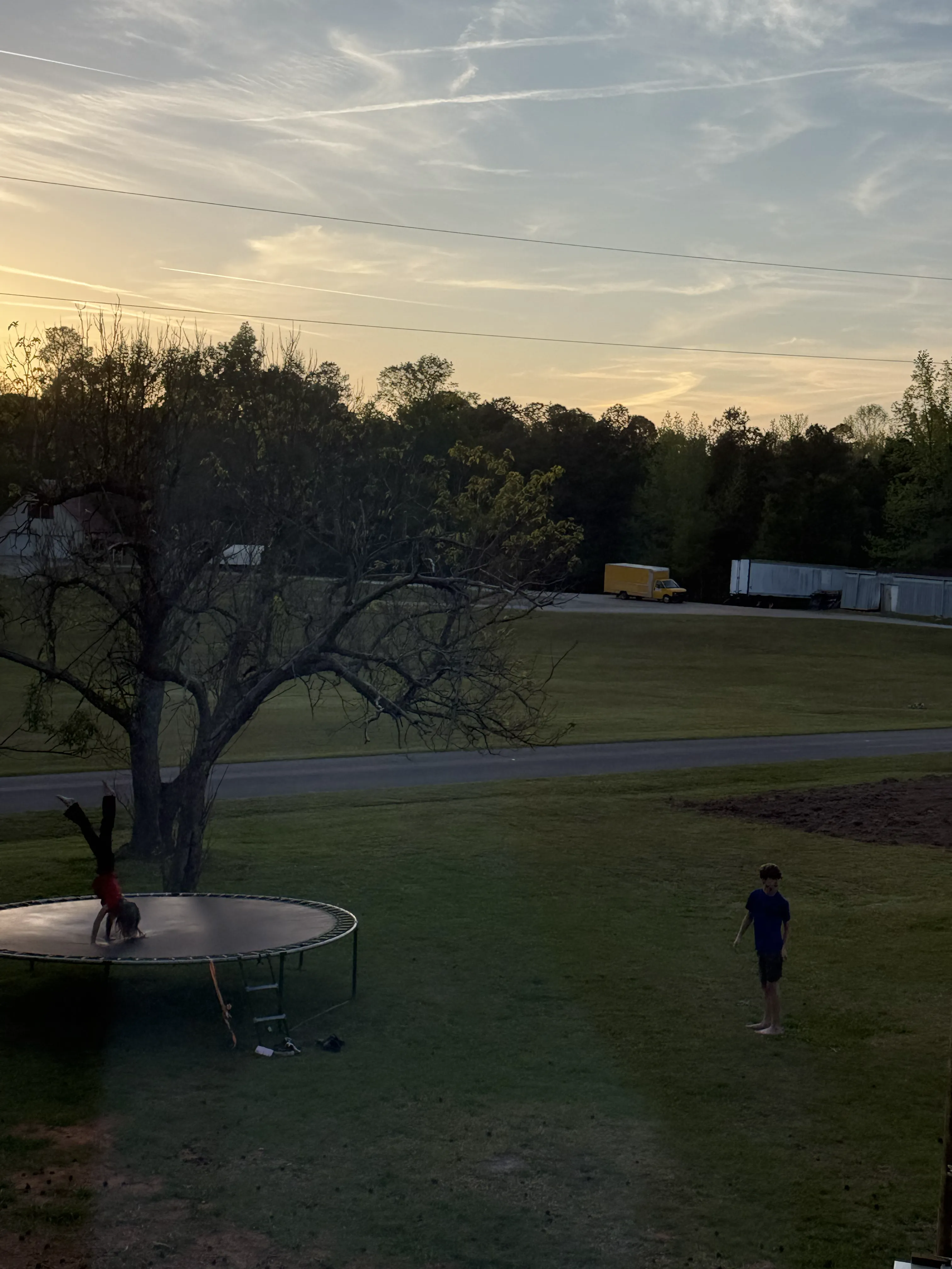 Children playing in the yard at dusk, viewed through a window
