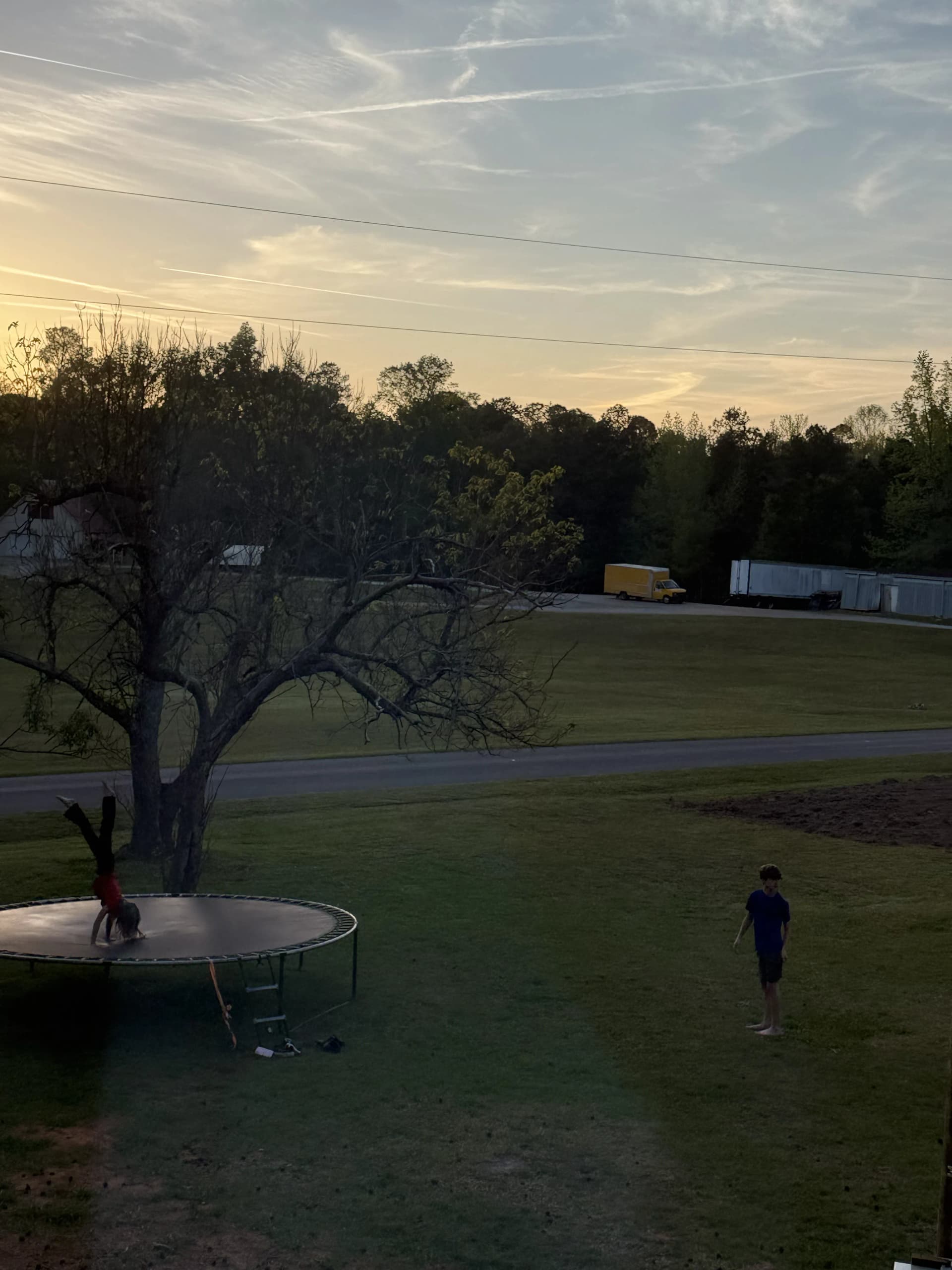 Children playing in the yard at dusk, viewed through a window