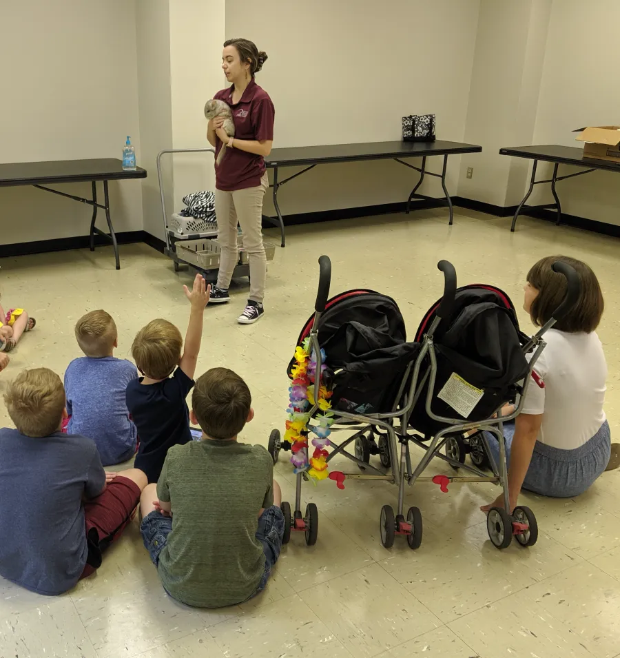 Museum staff holding a chinchilla for a group of children during a birthday party at the Anniston Museum of Natural History