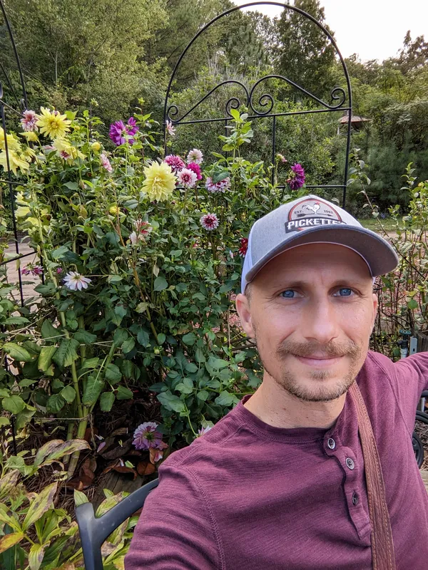 Matt Headley in front of blooming dahlias at Longleaf Botanical Gardens