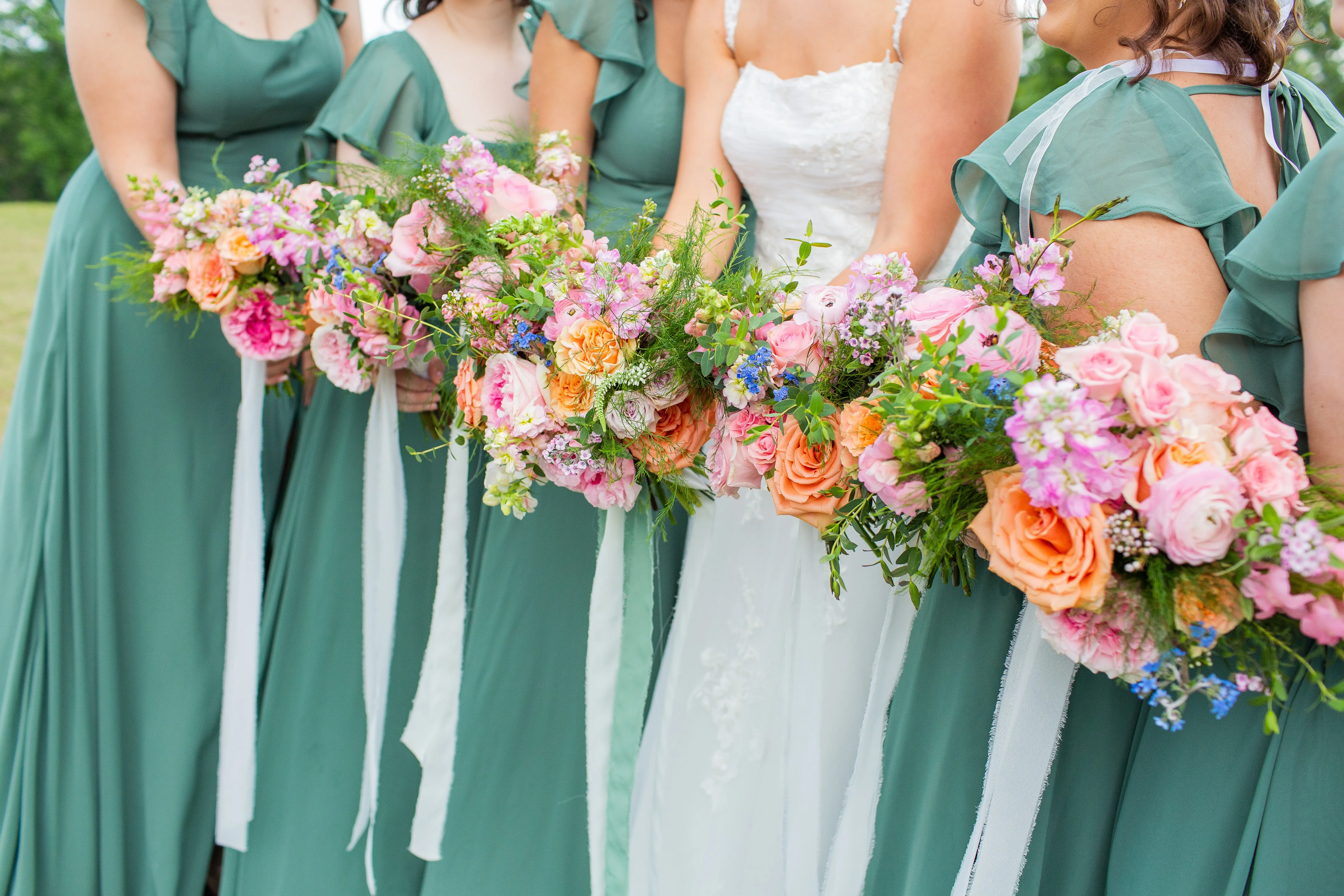 Bridesmaids holding lush pink, coral, and peach bouquets at Sonny Jenkins's wedding